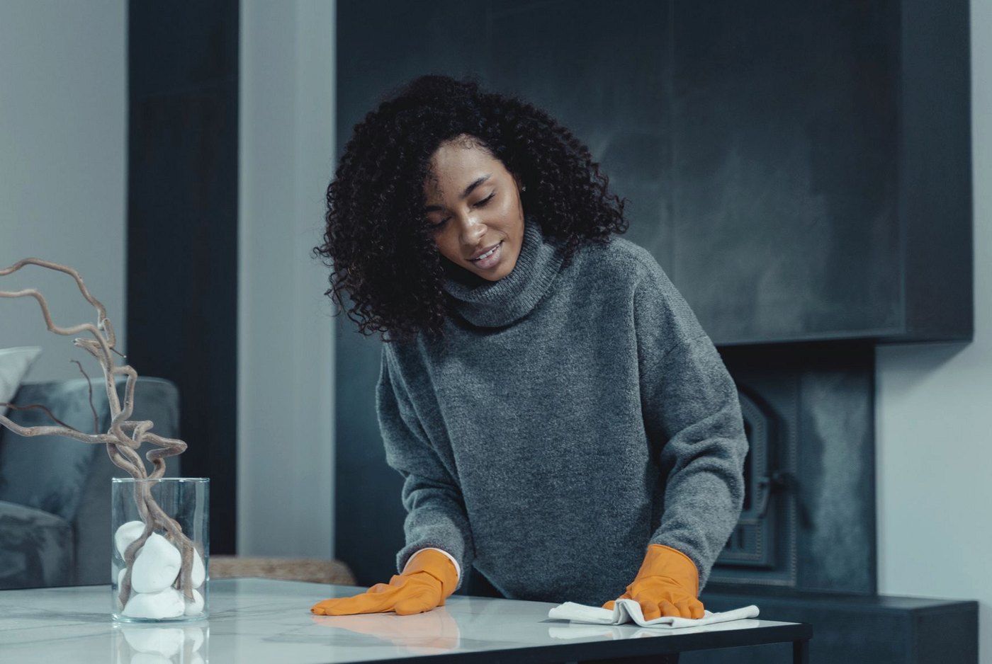 Cleaner in gloves wiping a living room coffee table