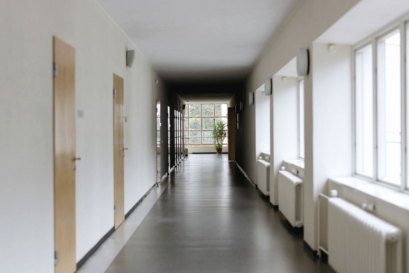 Empty school corridor with wooden classroom doors, radiators and a polished floor